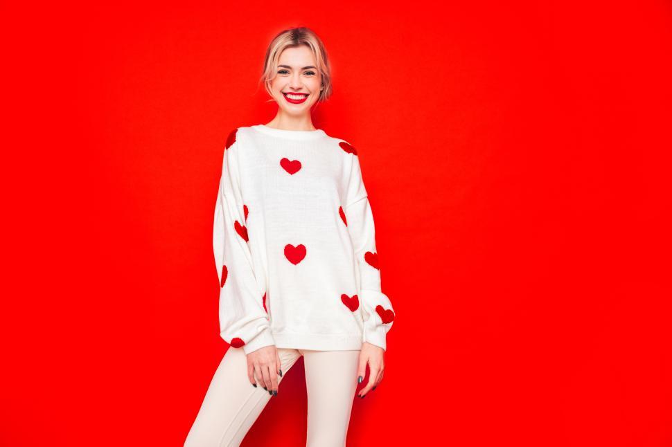 Free Image of Blonde woman in heart-patterned sweater on red background 