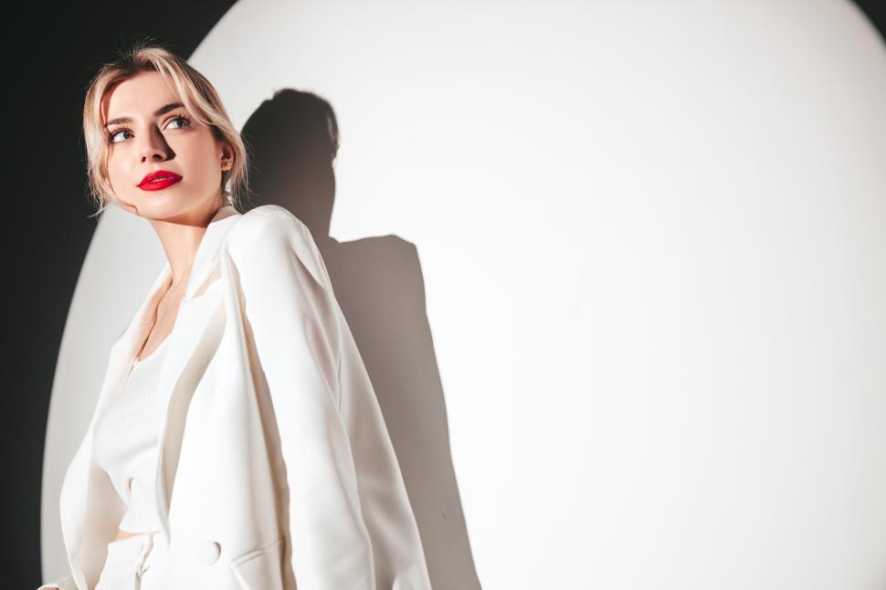 Free Image of Thoughtful woman in white suit in front of spotlight. 
