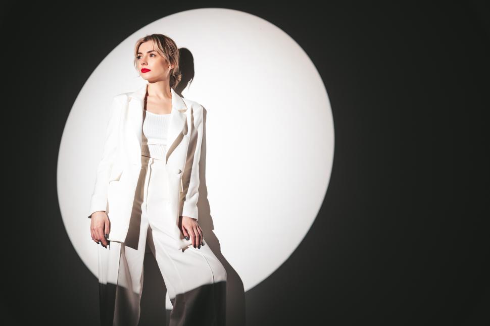 Free Image of Elegant woman posing in white suit with spotlight. 