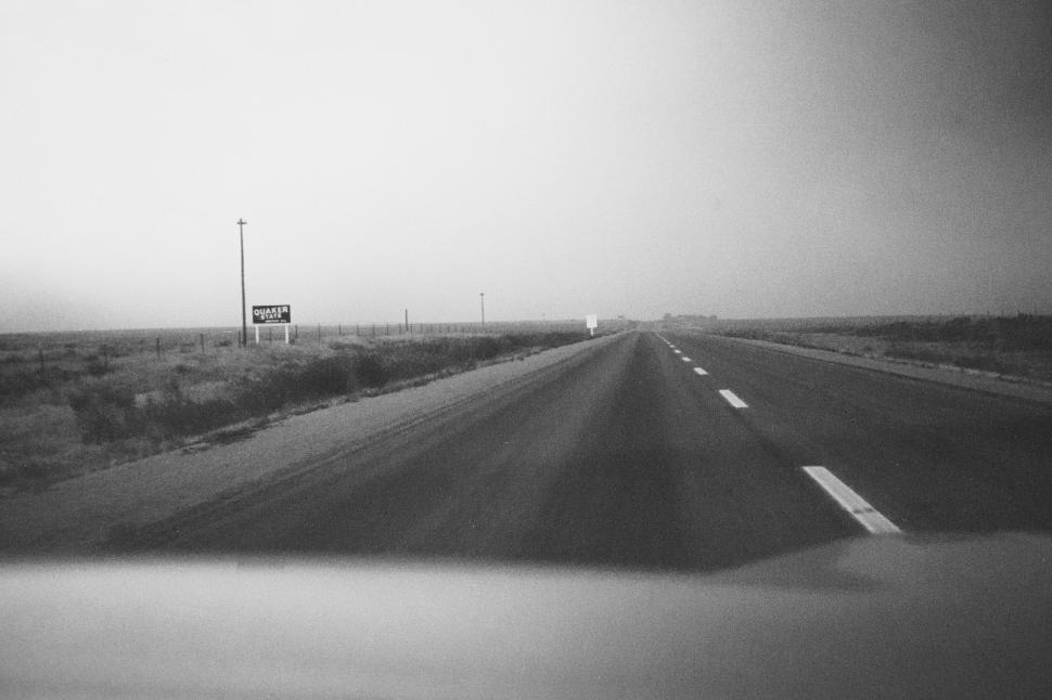 Free Image of Empty highway with a distant sign under a gray sky 