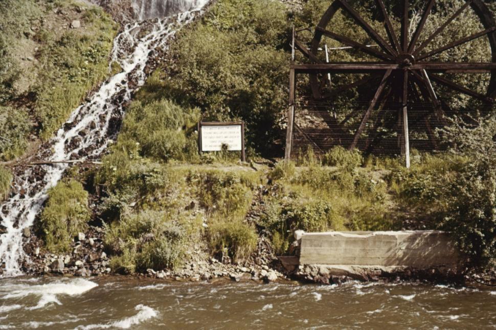 Free Image of Waterfall and old wheel structure by flowing river 