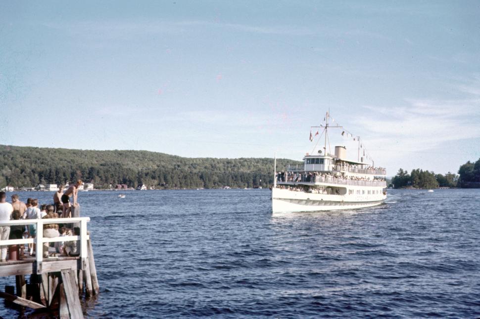 Free Image of Crowded boat approaches a pier on a calm blue lake. 