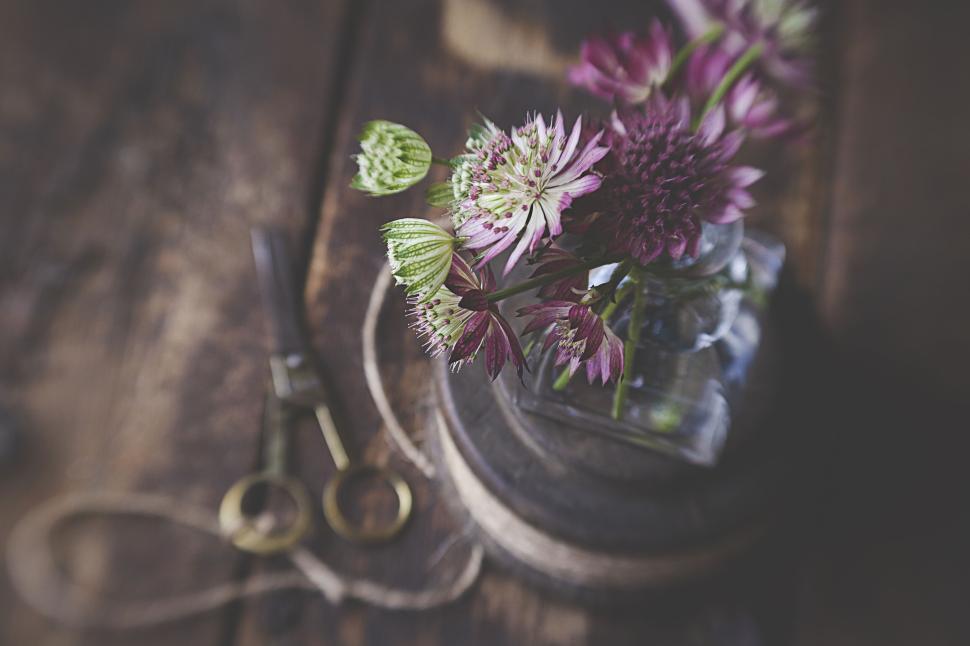 Free Image of Pink and white flowers in a glass container on wooden surface. 