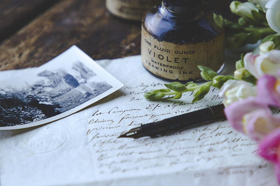 Free Image of Vintage ink bottle with letters, flowers, and photo. 