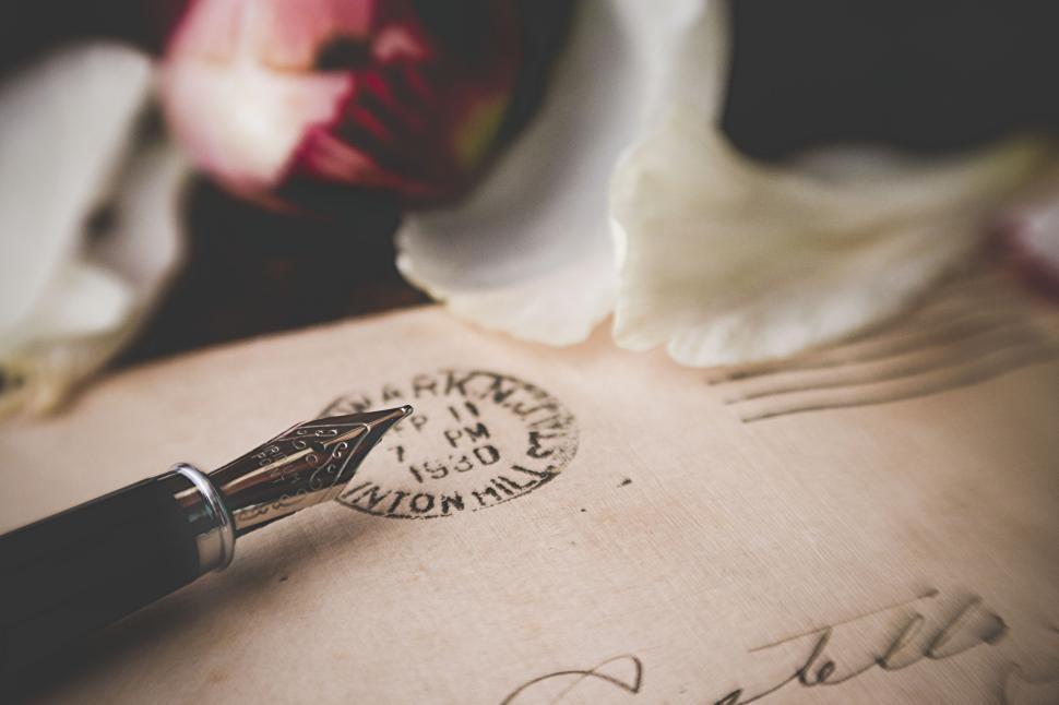 Free Image of Fountain pen and stamped letter with petals nearby. 