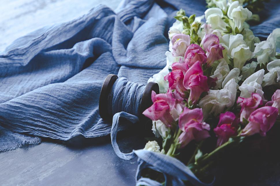Free Image of Colorful flowers and blue fabric with a wooden spool 