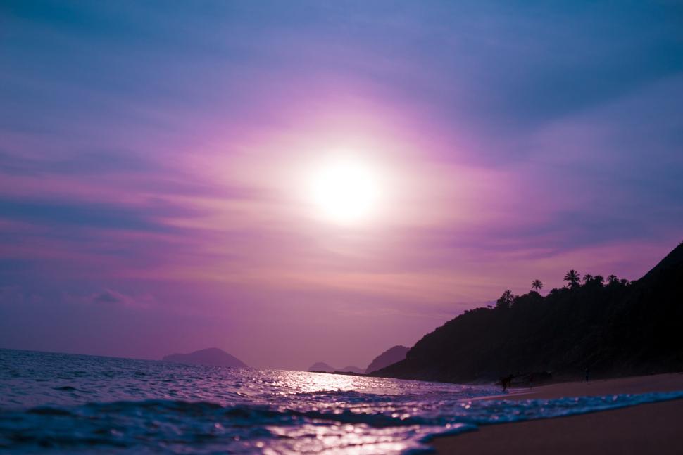 Free Image of Beautiful sunset over a beach with purple-hued sky. 