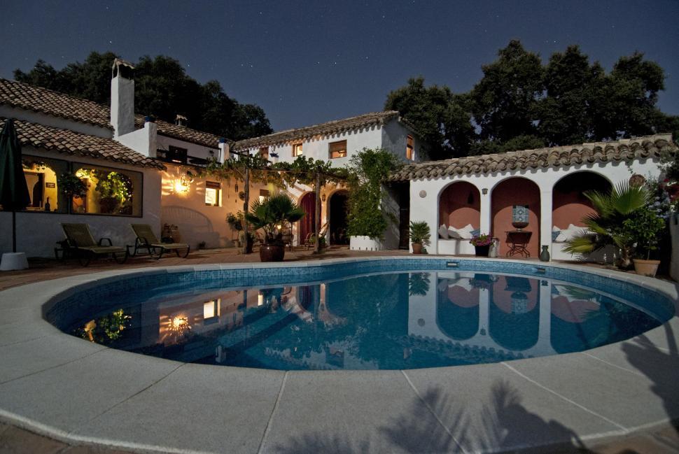 Free Image of Cozy villa with pool illuminated at night in a courtyard 