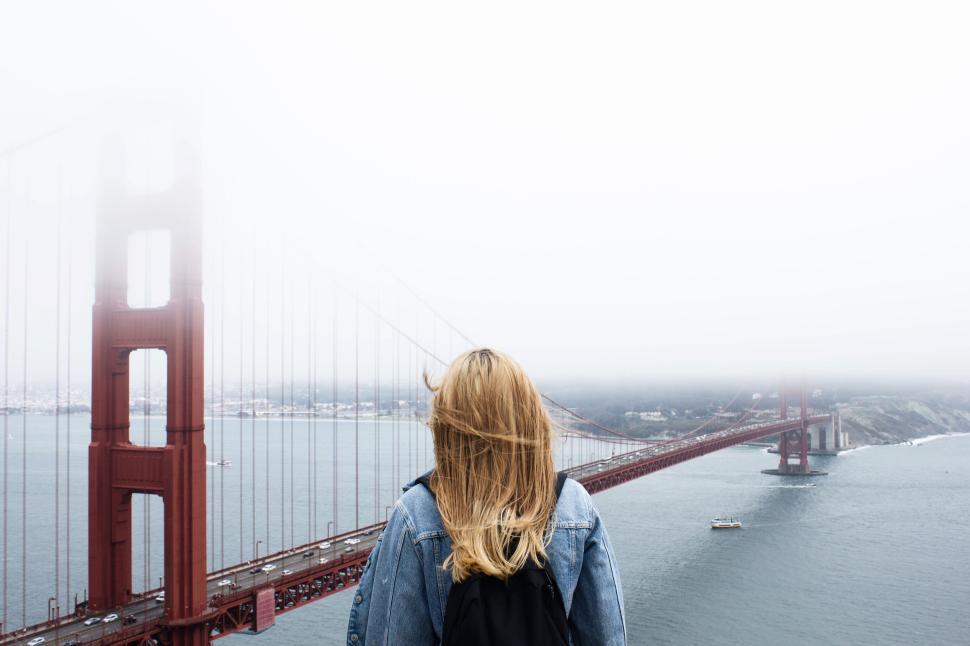Free Image of Woman overlooking the fog-covered Golden Gate Bridge 