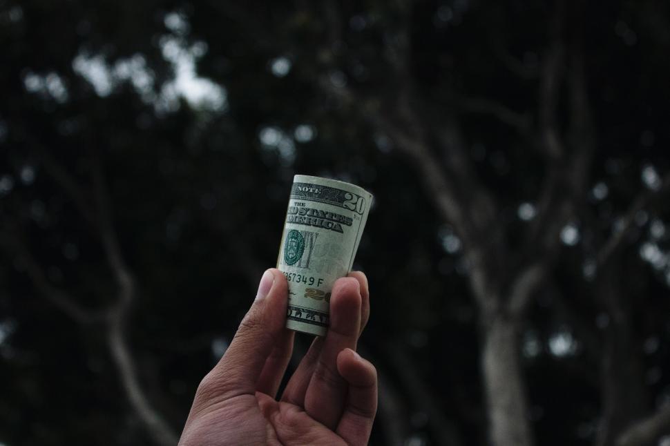 Free Image of Hand holding a rolled US dollar bill symbolic gesture 