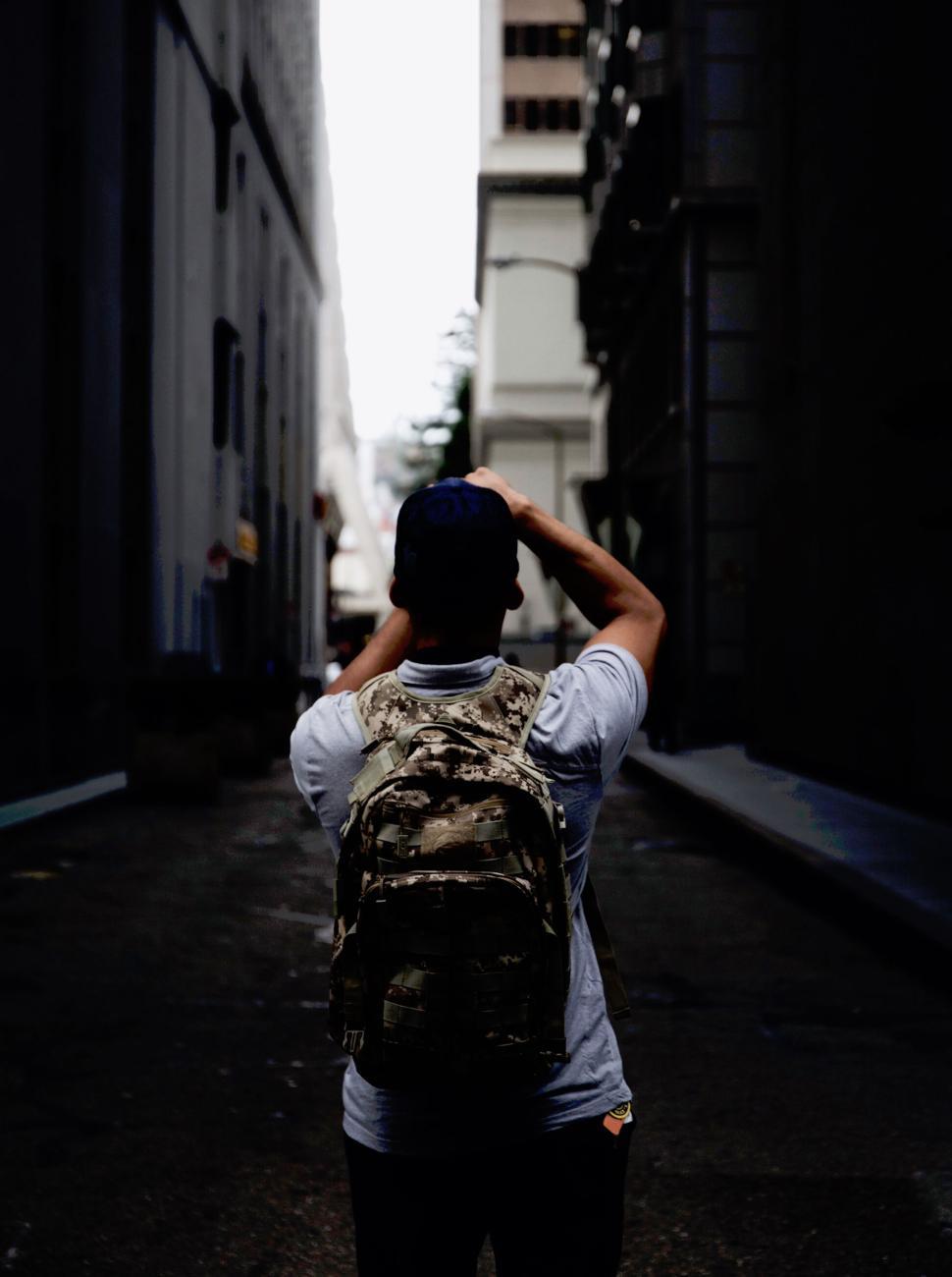 Free Image of Back view of a person in alley taking a photo 