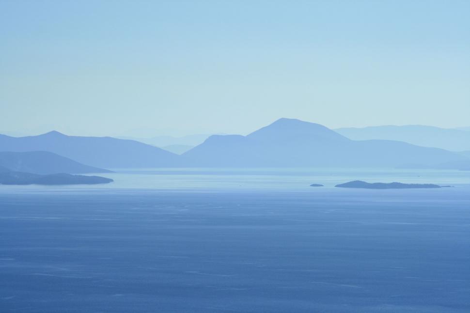 Free Image of Blue tinted hilly landscape with water in foreground 