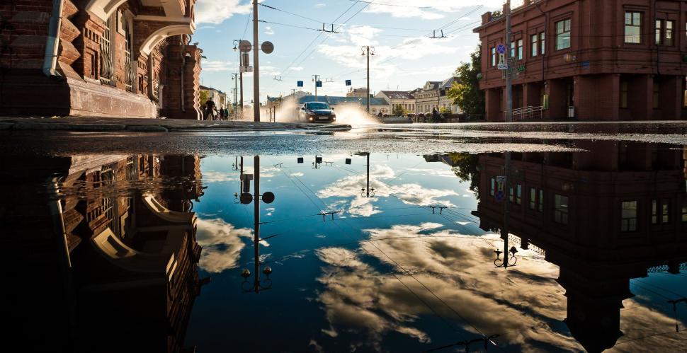 Free Image of City street reflection in puddle showing urban scenery 
