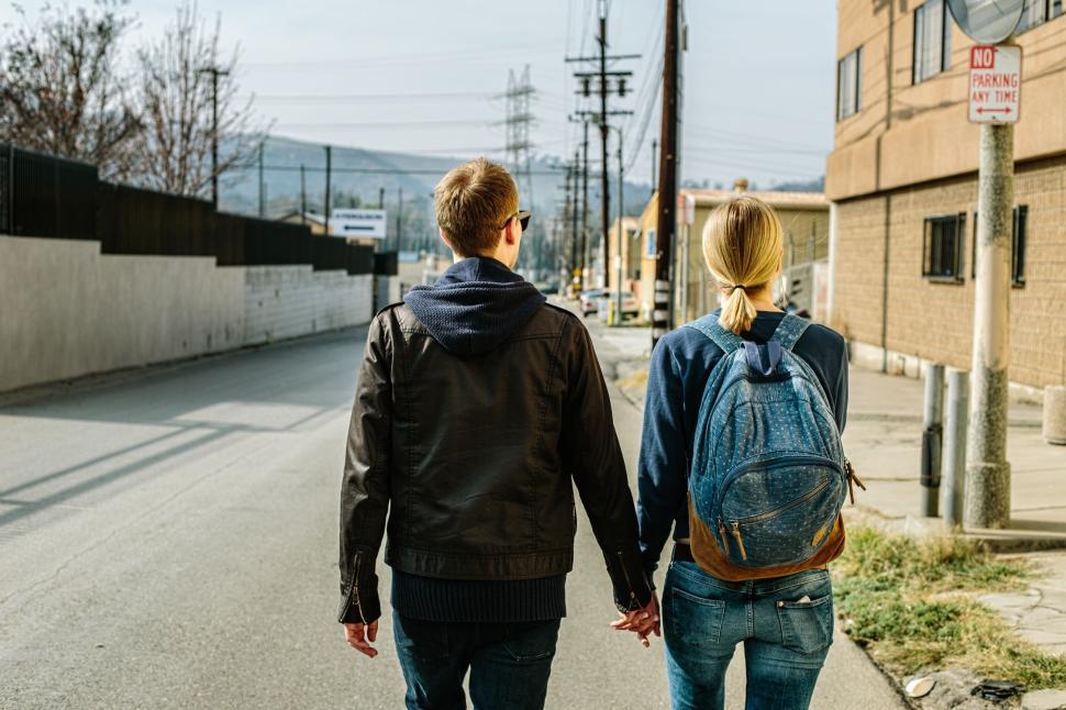 Free Image of Couple holding hands walking down the street 