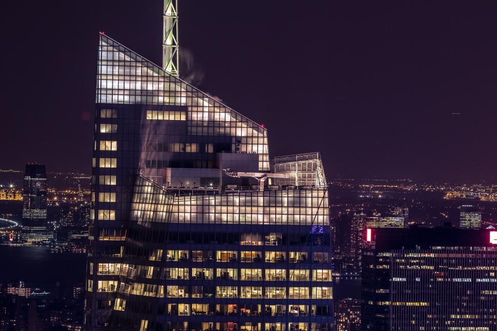 Free Image of Lit-up angular skyscraper with night view of the city 