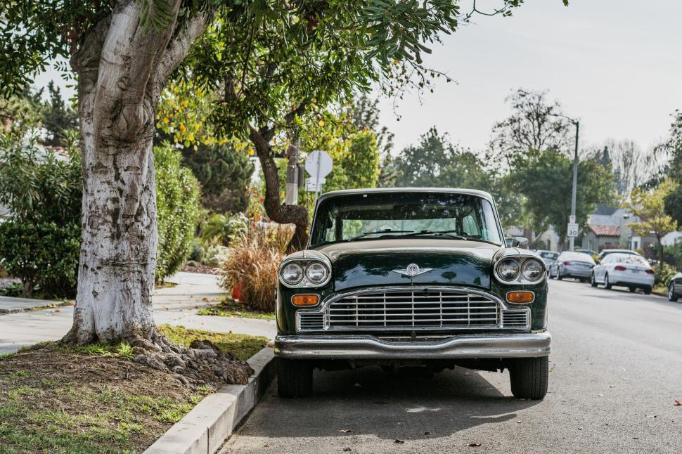 Free Image of Classic car parked under tree on suburban street view. 