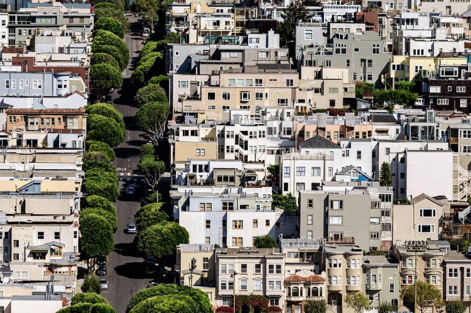 Free Image of Aerial view of densely packed buildings with green trees. 