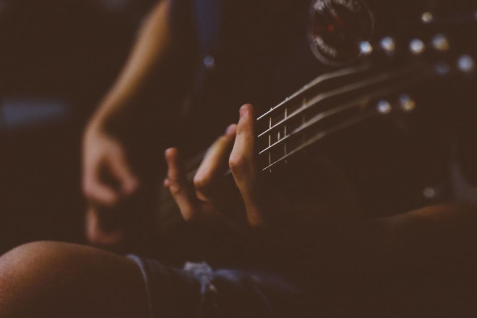 Free Image of Person playing a bass guitar captured in a dark room 