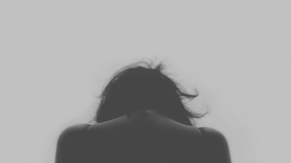 Free Image of Silhouette of person with head down against grey background 