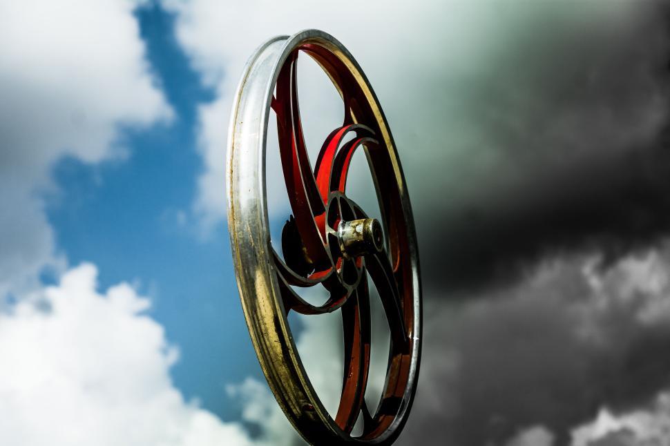 Free Image of Vintage metal wheel against a dramatic cloudy sky. 