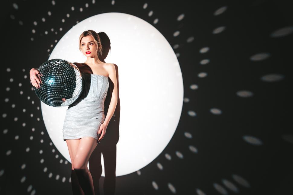 Free Image of Elegant woman in silver dress with disco ball pose. 