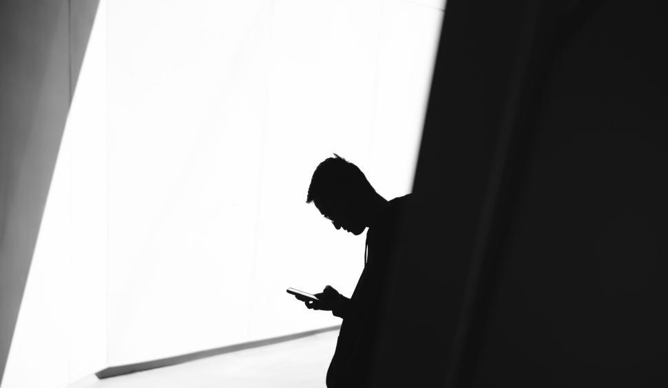 Free Image of Silhouetted person holding a device in a modern building. 
