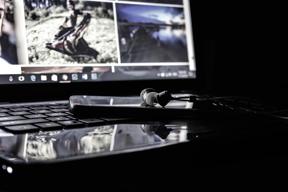 Free Image of Laptop with headphones and smartphone reflecting screen. 