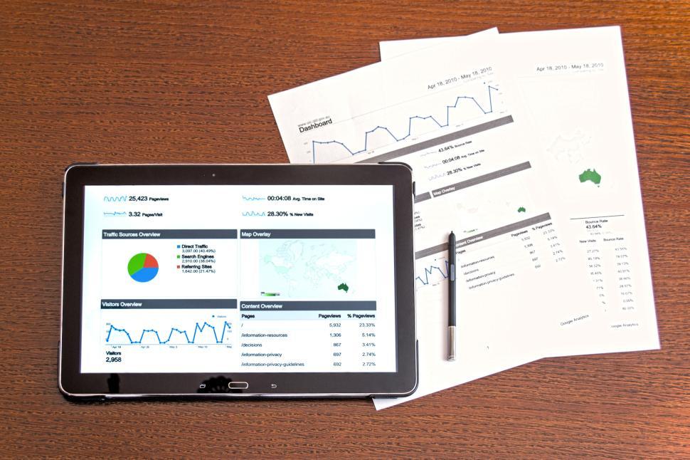 Free Image of Tablet with analytics dashboard and printed reports and pen. 