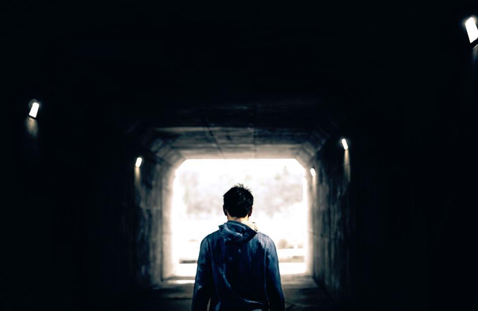 Free Image of Person walking into illuminated concrete tunnel exit. 