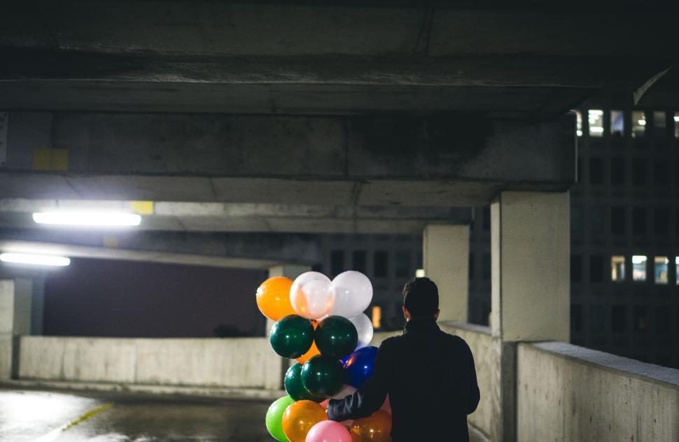 Free Image of Person with colorful balloons in parking garage. 
