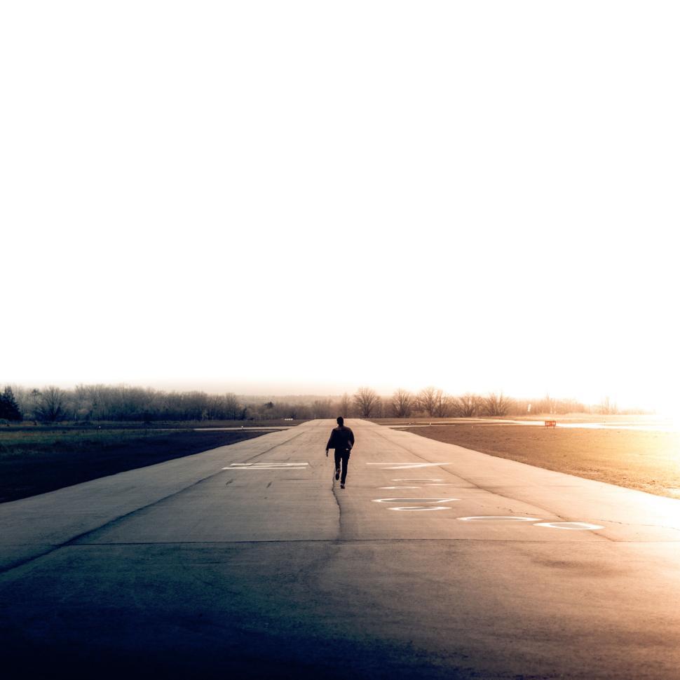 Free Image of Backview of person walking along an empty runway. 