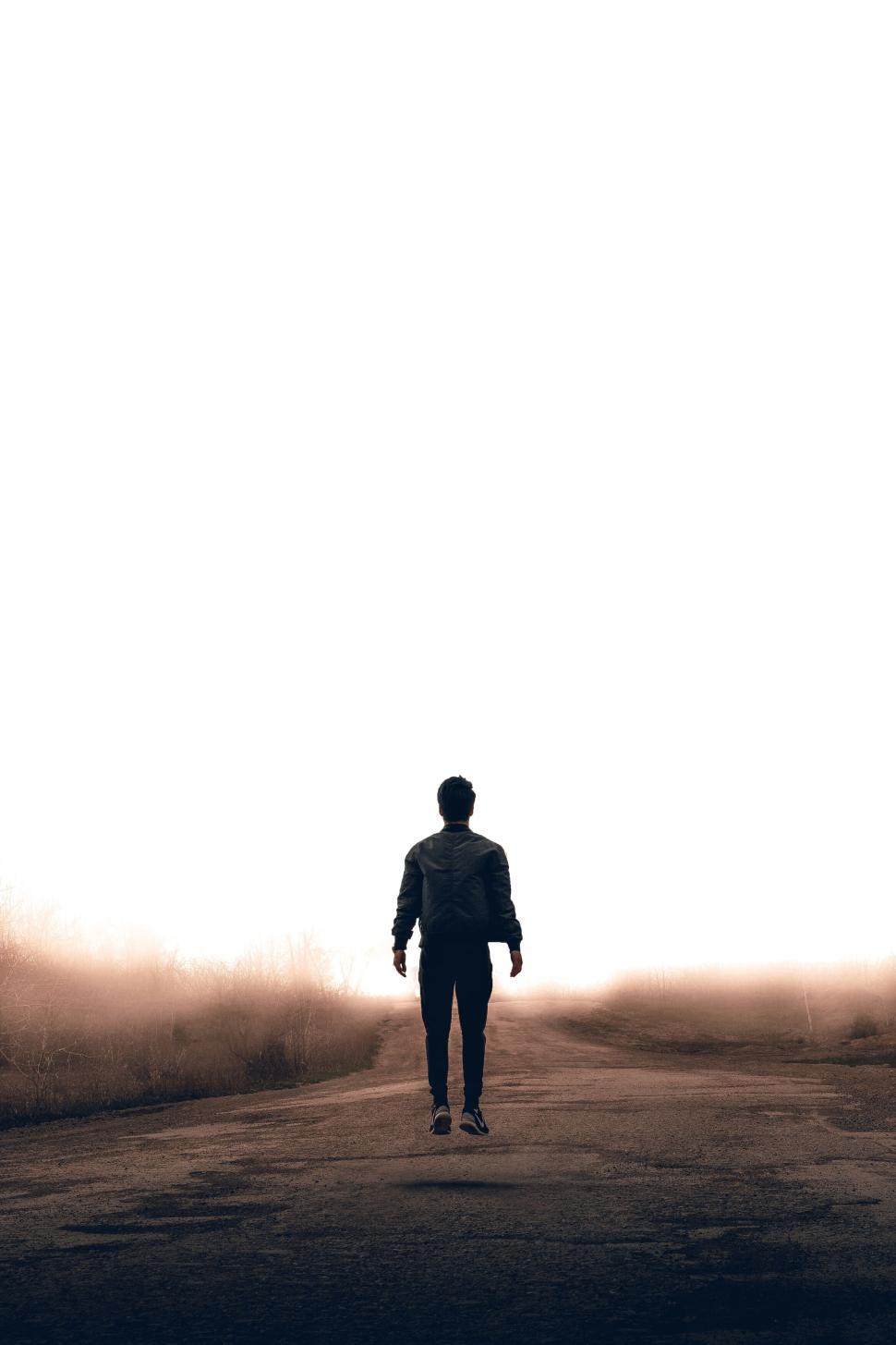 Free Image of Person standing alone on an empty road at sunrise. 