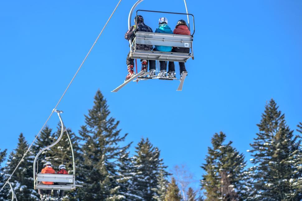 Free Image of Ski lift carrying skiers over a snow-covered landscape 