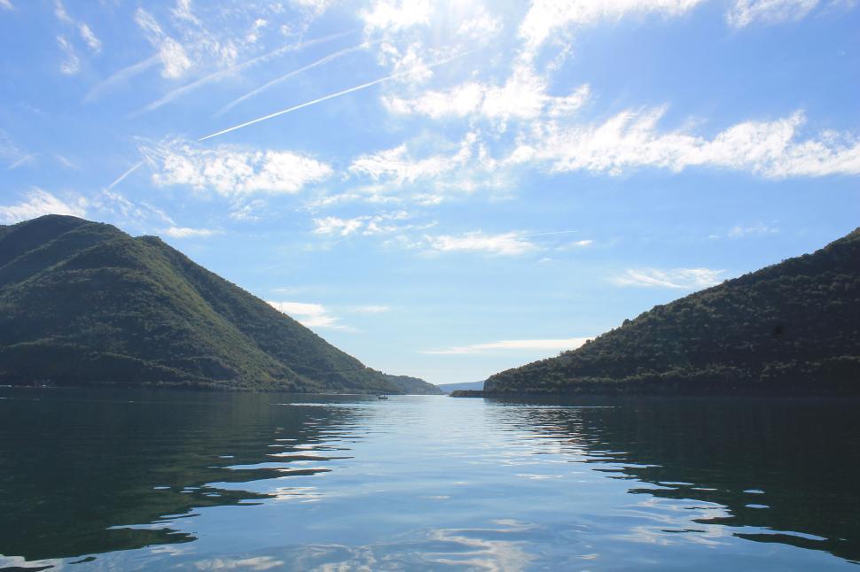 Free Image of Calm lake under clear sky nestled between two hills. 
