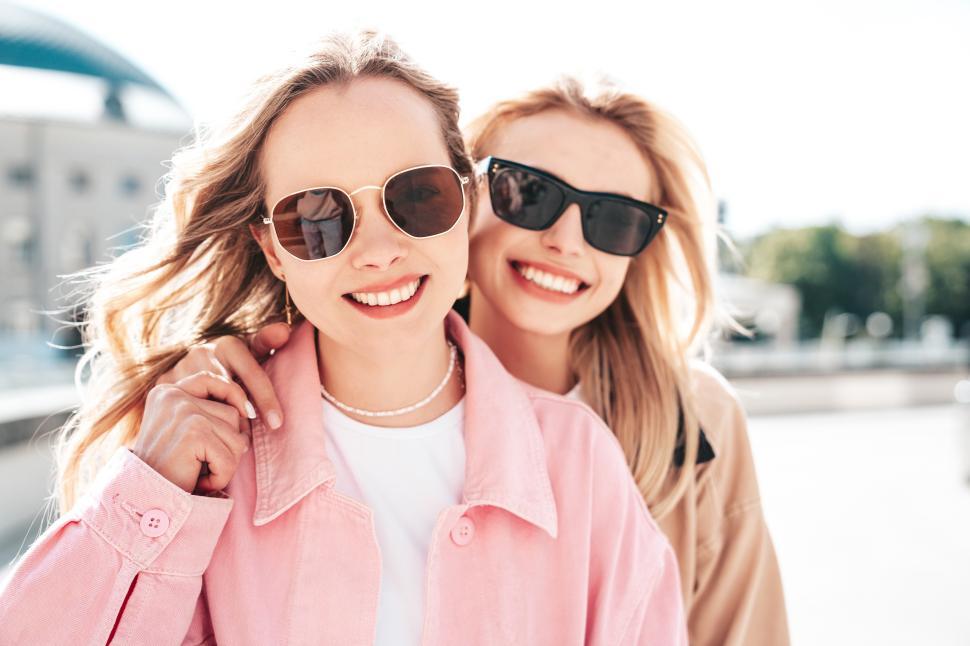 Free Image of Two young women hold hands while walking outside 