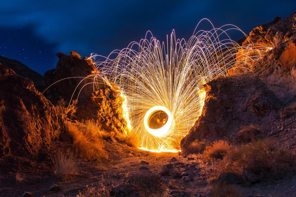 Free Image of Sparks fly in a rocky canyon under the night sky 