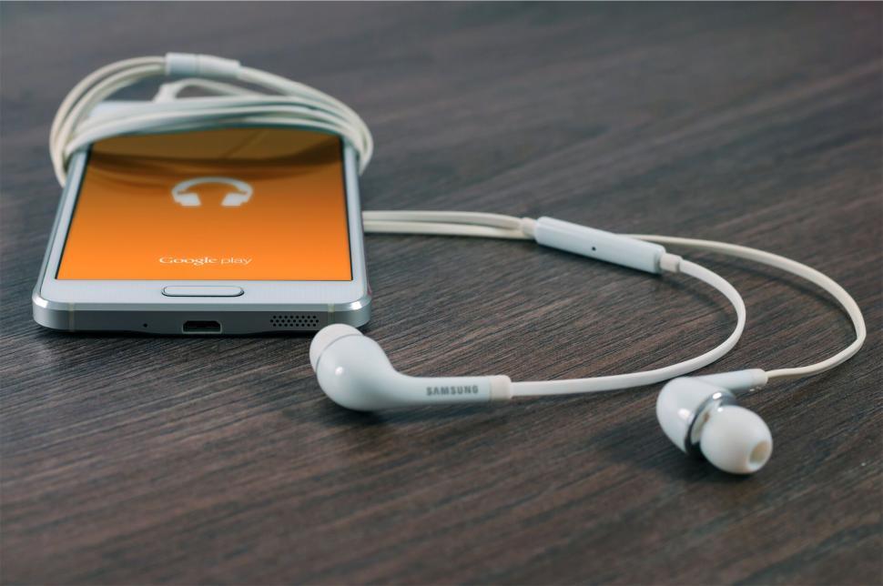 Free Image of Earphones wrapped around smartphone with music app open. 
