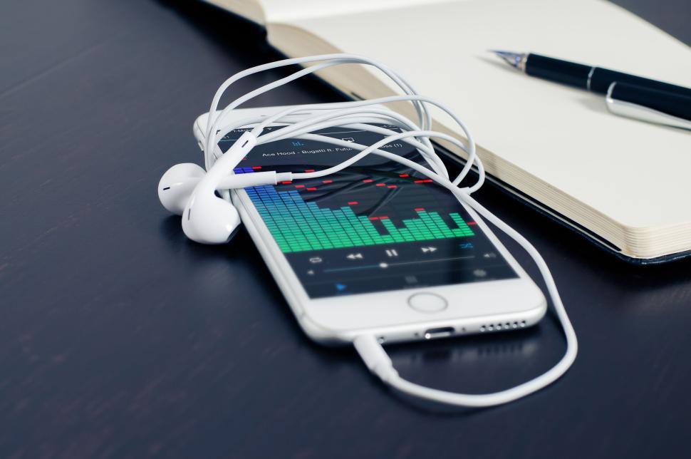 Free Image of Smartphone with earphones, music app and a notebook. 