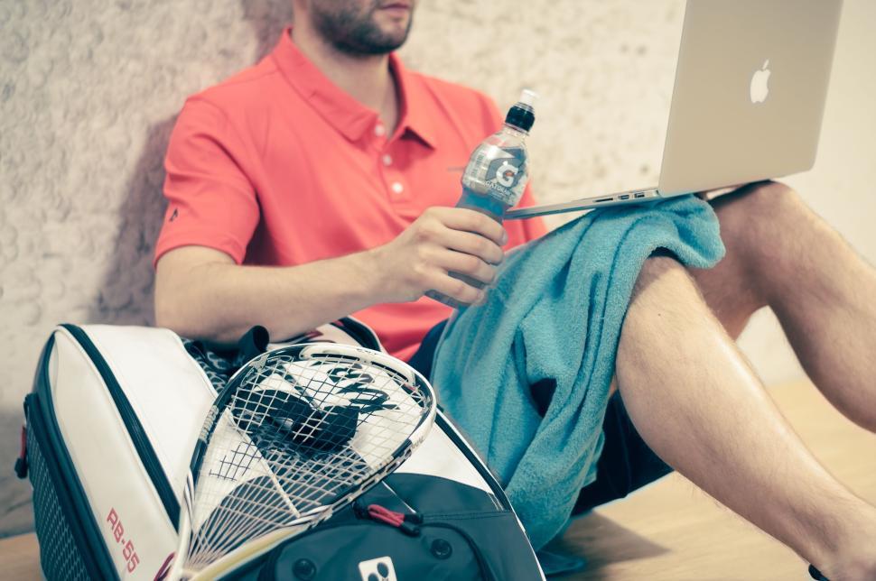 Free Image of Man with laptop and squash gear resting on the floor. 