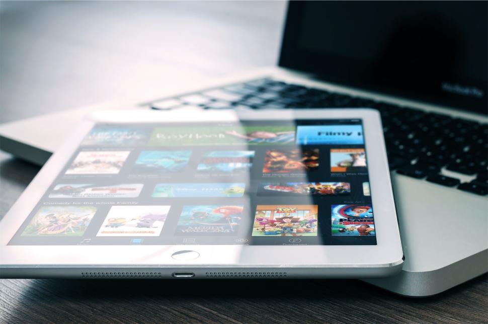 Free Image of Tablet showing various media content next to a laptop. 