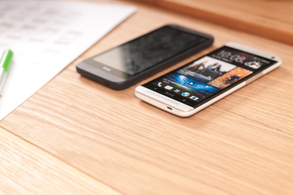 Free Image of Two smartphones placed on a wooden table side by side. 