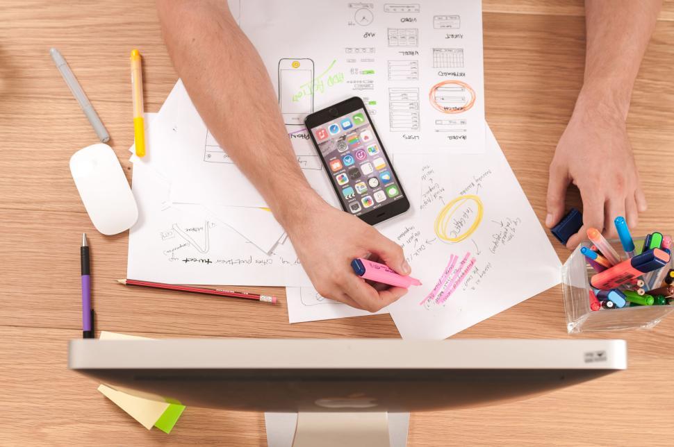 Free Image of Person highlighting notes and smartphone on desk setup 