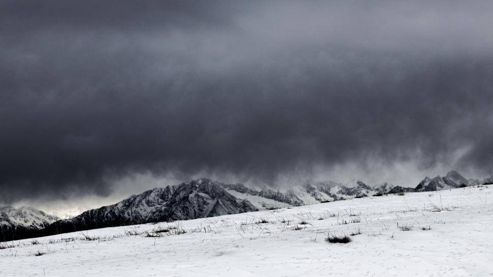 Free Image of Dramatic snow-covered mountains under stormy sky. 