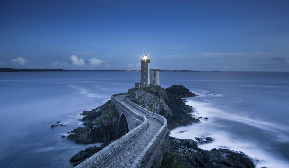 Free Image of Lighthouse at the end of a long curved stone pathway 