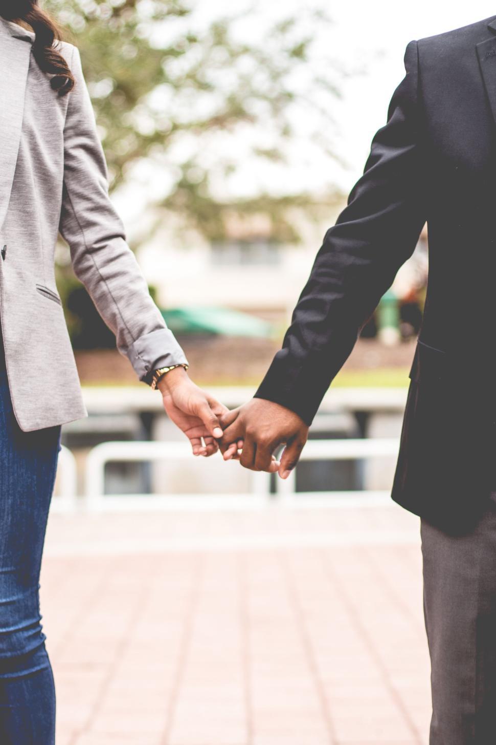 Free Image of Couple holding hands walking together outdoors 