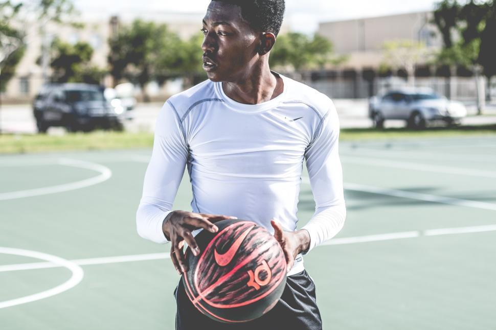 Free Image of Athletic person holding a basketball on outdoor court 
