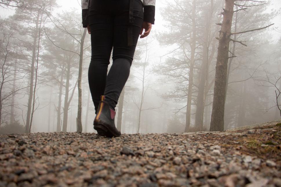 Free Image of Person walking in foggy forest path wearing hiking boots 