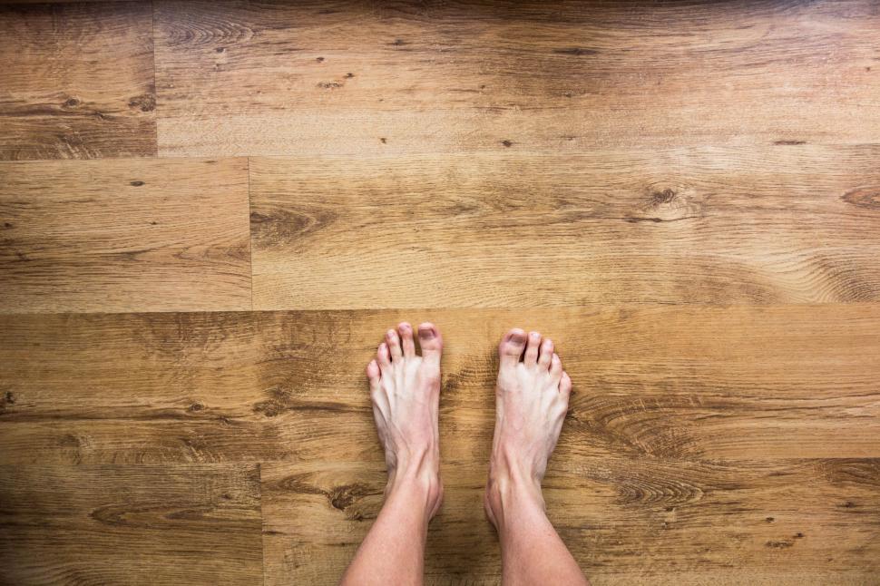 Free Image of Barefoot feet on wooden floor showing unique perspective 