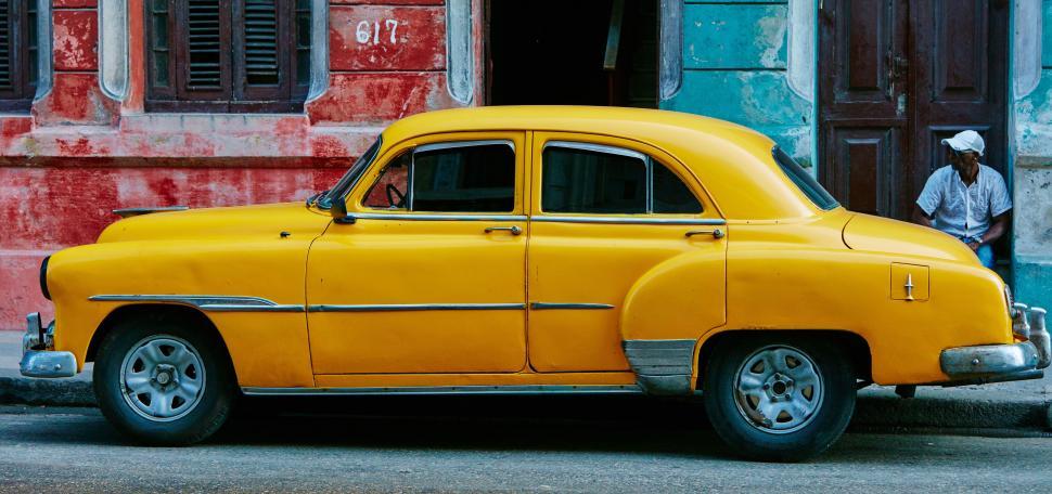 Free Image of Classic yellow vintage car parked beside vibrant wall 