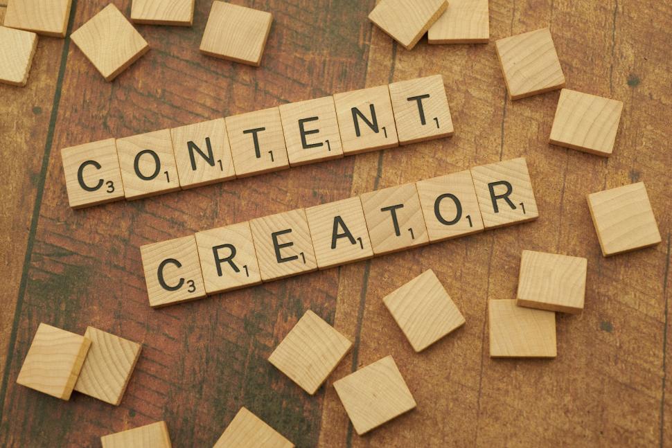 Free Image of Content Creator  spelled with Scrabble tiles on wooden background. 